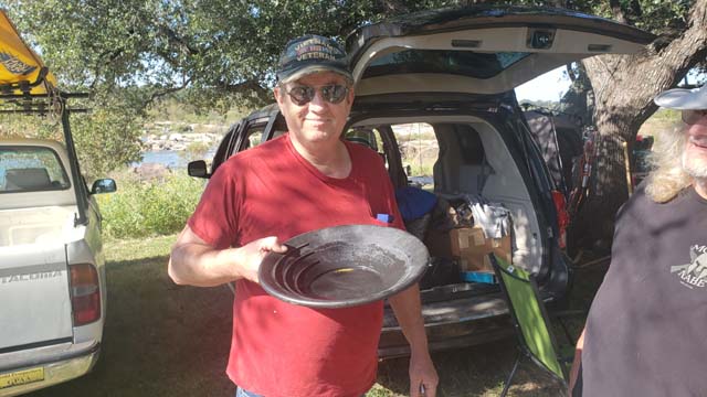 Larry Malone holding a green gold pan showing his find at the October 2024 Halliburton Outing